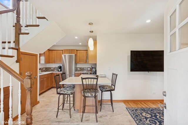 kitchen with freestanding refrigerator, a peninsula, a kitchen breakfast bar, recessed lighting, and light countertops