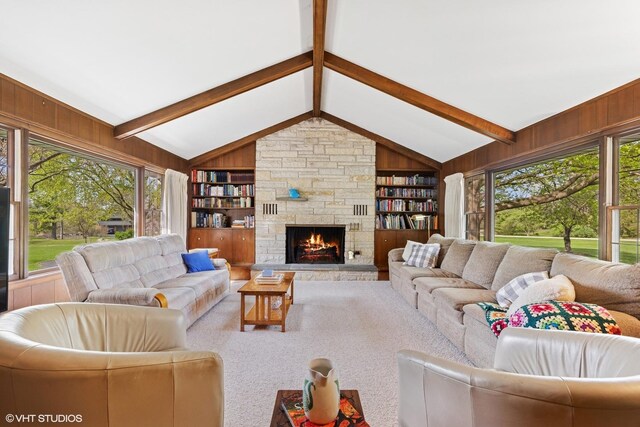 living area featuring lofted ceiling with beams, a fireplace, wooden walls, and built in shelves