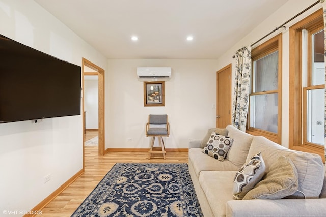 living room with recessed lighting, baseboards, light wood-style flooring, and a wall mounted air conditioner