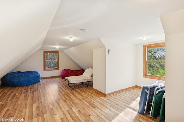 bedroom featuring baseboards, lofted ceiling, multiple windows, and light wood finished floors
