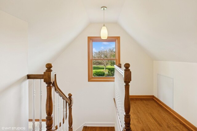 stairway with baseboards, lofted ceiling, and wood finished floors