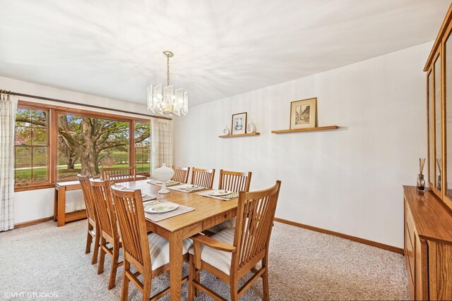 dining area with baseboards, a notable chandelier, and light carpet