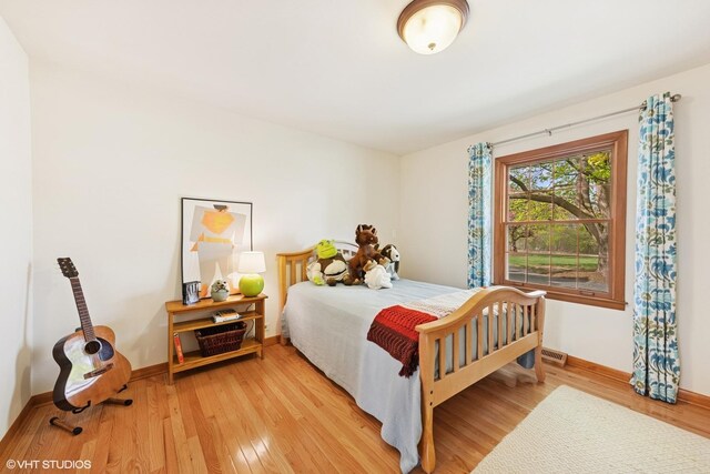 bedroom with baseboards, light wood finished floors, and visible vents