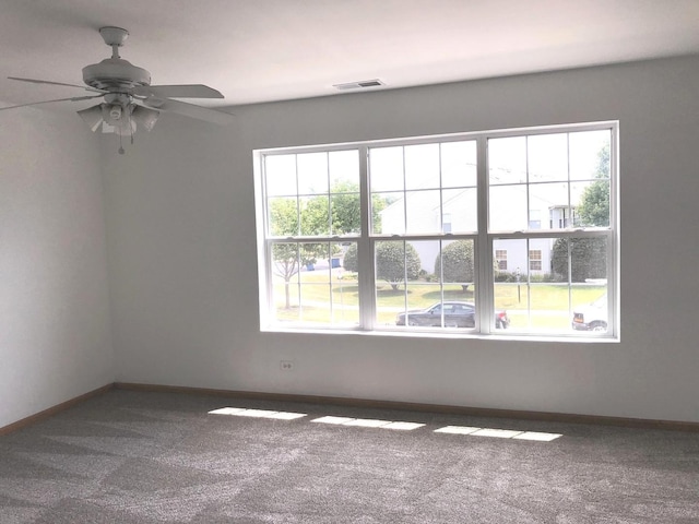 spare room featuring plenty of natural light, a ceiling fan, carpet floors, and visible vents