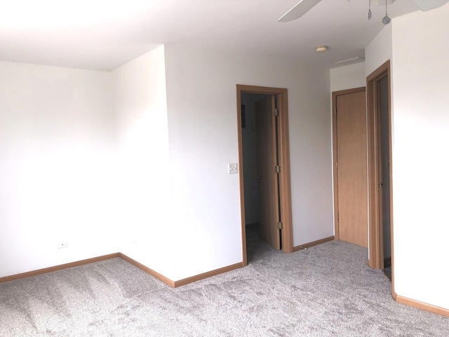 carpeted empty room with ceiling fan and baseboards