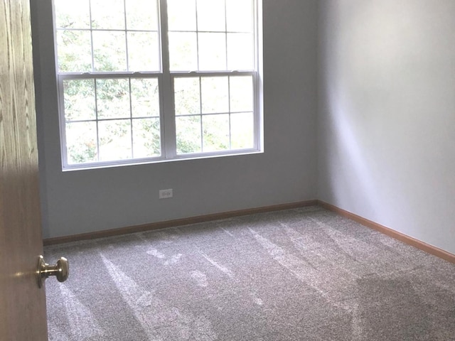carpeted spare room with baseboards and a wealth of natural light