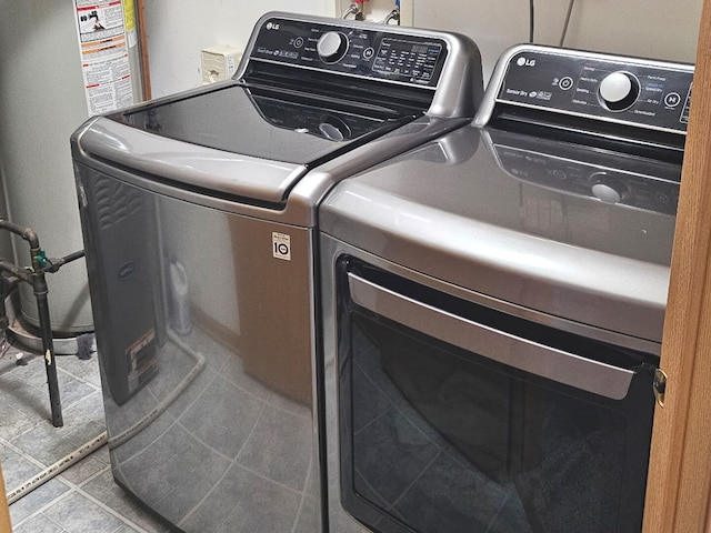 laundry area with water heater, tile patterned floors, laundry area, and washing machine and dryer