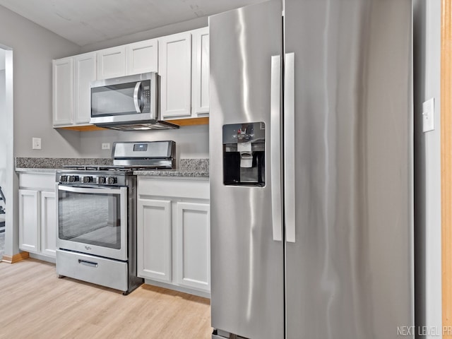 kitchen with light stone countertops, light wood-style flooring, white cabinetry, and stainless steel appliances