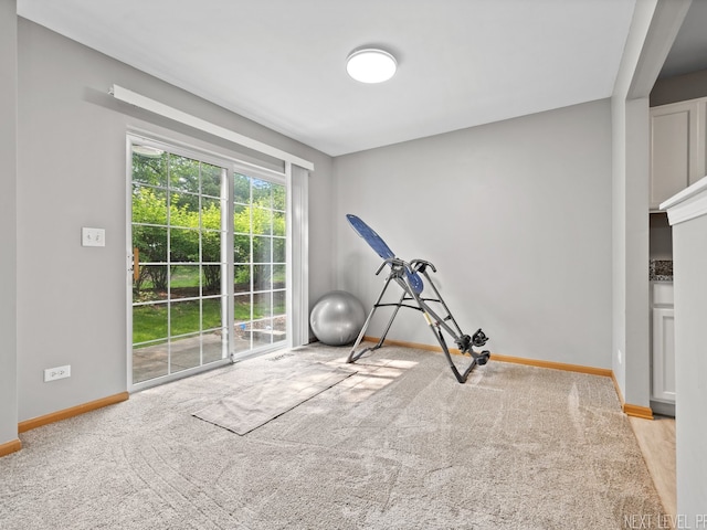 exercise room with baseboards and carpet floors
