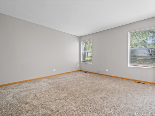 carpeted spare room featuring baseboards and visible vents