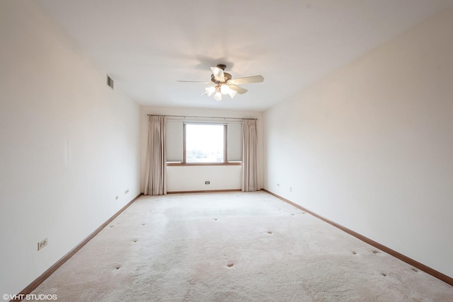 empty room with baseboards, ceiling fan, light carpet, and visible vents
