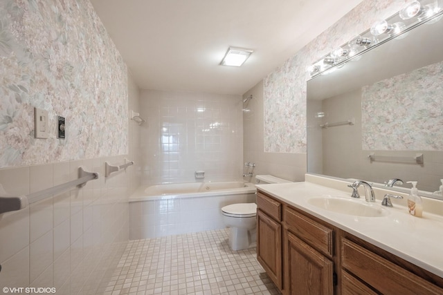 full bathroom featuring vanity, toilet, tile patterned floors, tiled shower / bath, and tile walls
