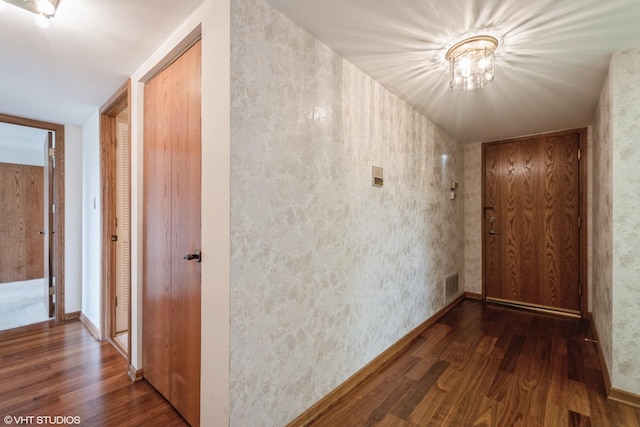 corridor featuring visible vents, wood finished floors, and a notable chandelier