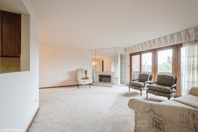 living area with carpet floors, baseboards, and a glass covered fireplace