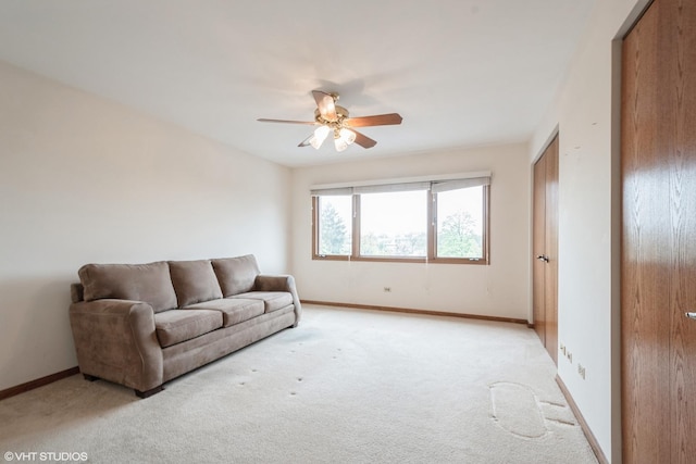 living room with baseboards, a ceiling fan, and light colored carpet