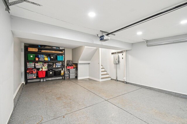garage with baseboards, a garage door opener, and recessed lighting