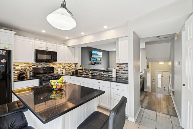 kitchen featuring a sink, decorative backsplash, a breakfast bar area, and black appliances