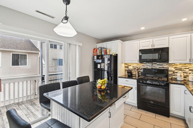 kitchen featuring visible vents, decorative backsplash, white cabinetry, and black appliances