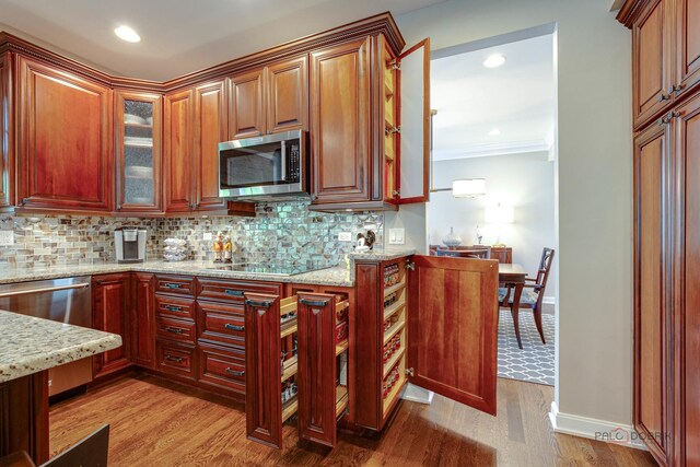 2550 Bayswater Cir, Gurnee, IL 60031 - kitchen featuring appliances with stainless steel finishes, light stone countertops, light wood-style flooring, backsplash, and crown molding