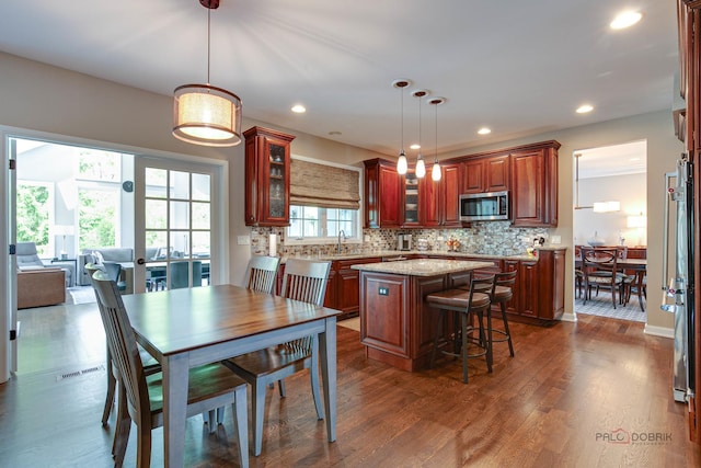 2550 Bayswater Cir, Gurnee, IL 60031 - kitchen featuring stainless steel microwave, a kitchen island, a sink, glass insert cabinets, and decorative backsplash