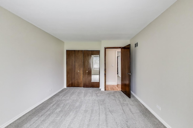 unfurnished bedroom with baseboards, visible vents, light carpet, and a closet