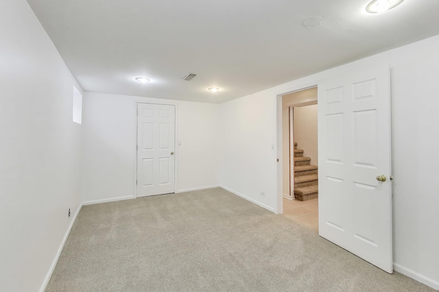finished basement with baseboards, stairs, and light colored carpet