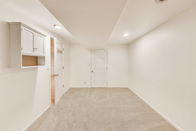 below grade area featuring recessed lighting, baseboards, and light colored carpet