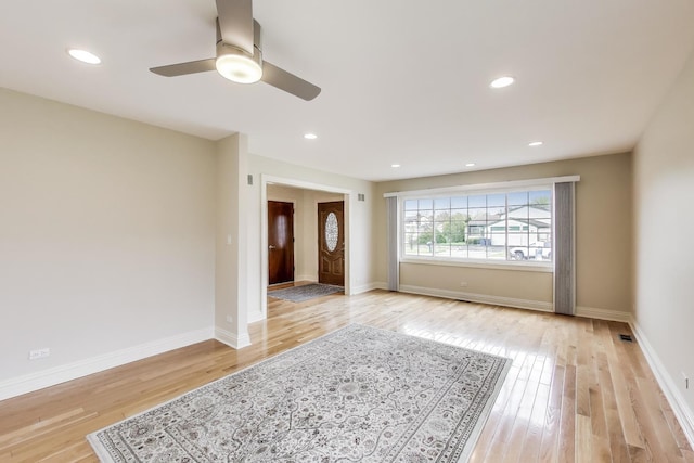spare room featuring baseboards, light wood finished floors, and ceiling fan
