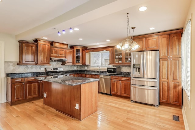kitchen featuring under cabinet range hood, brown cabinets, appliances with stainless steel finishes, and visible vents