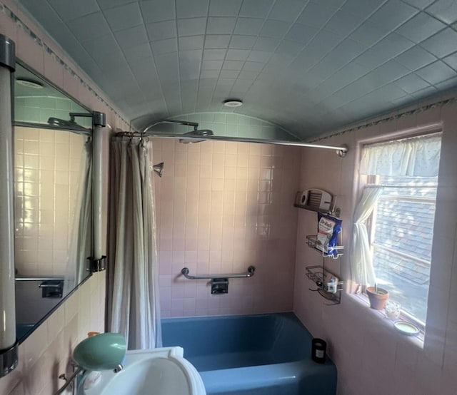 bathroom featuring shower / bath combination with curtain and lofted ceiling