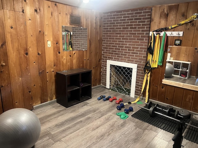 workout room featuring wood finished floors, wood walls, and a fireplace