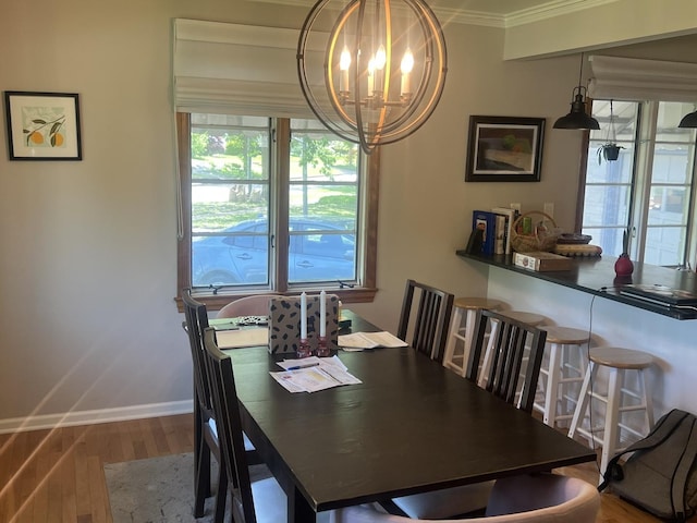dining space featuring a chandelier, wood finished floors, ornamental molding, healthy amount of natural light, and baseboards