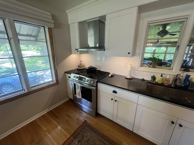 kitchen featuring stainless steel gas range oven, wall chimney exhaust hood, plenty of natural light, and tasteful backsplash