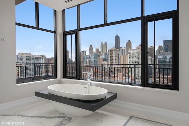 400 W Ontario St Unit 1801, Chicago, IL 60654 - bathroom featuring marble tiled flooring, a view of skyline, a freestanding bath, baseboards, and a high ceiling
