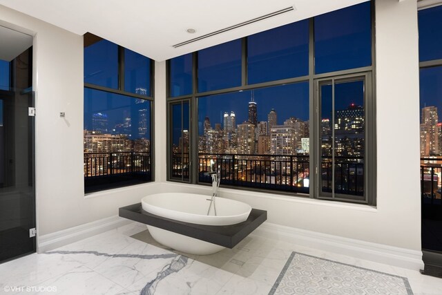 400 W Ontario St Unit 1801, Chicago, IL 60654 - bathroom featuring a view of city lights, marble tiled flooring, a freestanding tub, and baseboards
