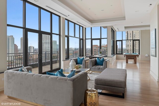 400 W Ontario St Unit 1801, Chicago, IL 60654 - living area featuring billiards table, light wood-type flooring, baseboards, a view of skyline, and a tray ceiling