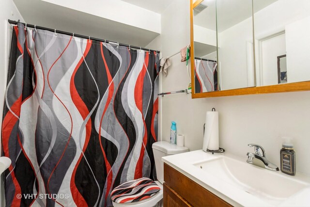 bathroom with toilet, visible vents, curtained shower, and vanity