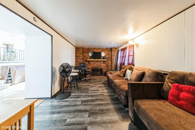 living area with a brick fireplace and wood finished floors