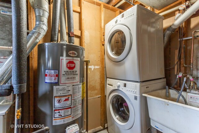 clothes washing area featuring laundry area, a sink, stacked washer / dryer, and water heater