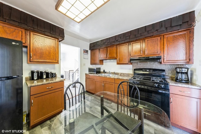 kitchen featuring tasteful backsplash, a sink, light countertops, black appliances, and under cabinet range hood
