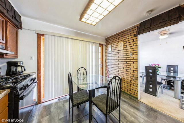 dining area featuring brick wall, visible vents, dark wood-style floors, and ceiling fan