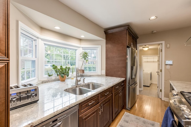 6700 N Monticello Ave, Lincolnwood, IL 60712 - kitchen featuring washing machine and clothes dryer, light stone countertops, appliances with stainless steel finishes, a sink, and light wood finished floors