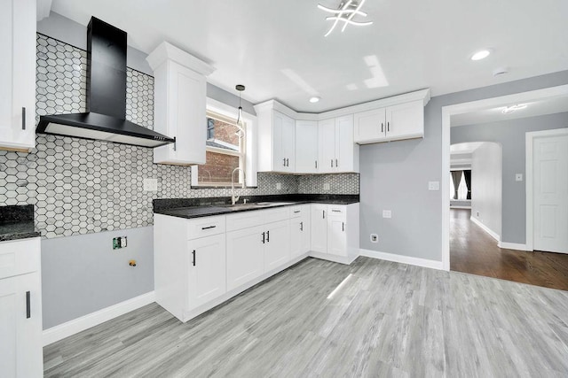 7315 S California Ave, Chicago, IL 60629 - kitchen featuring wall chimney range hood, dark countertops, a sink, light wood-type flooring, and backsplash