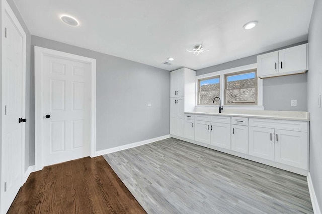 7315 S California Ave, Chicago, IL 60629 - kitchen with a sink, light countertops, white cabinetry, baseboards, and light wood-type flooring