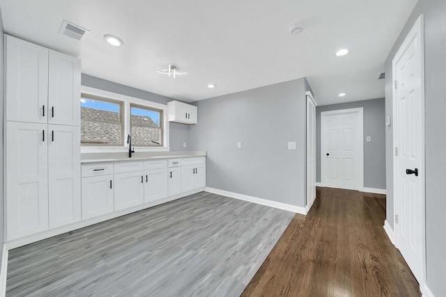 7315 S California Ave, Chicago, IL 60629 - kitchen with light countertops, baseboards, light wood-style flooring, and white cabinetry