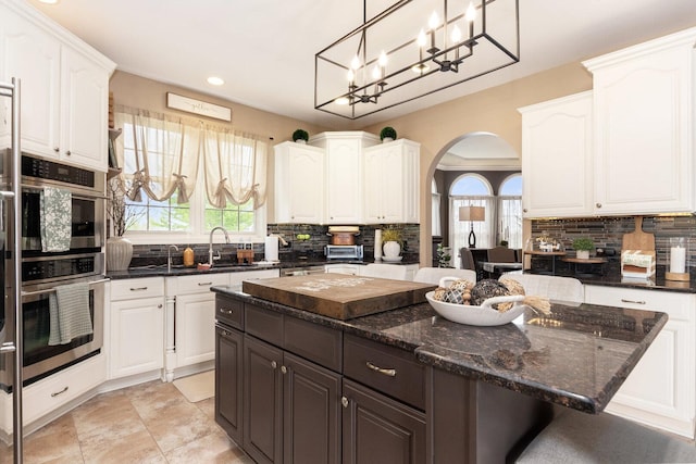 7659 Fairway Dr, Yorkville, IL 60560 - kitchen with arched walkways, backsplash, a kitchen island, and white cabinets