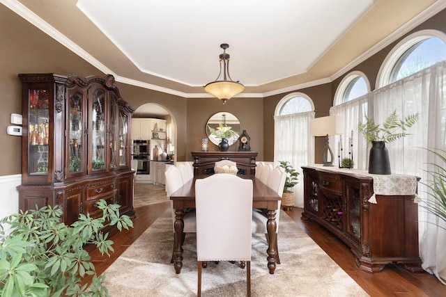 7659 Fairway Dr, Yorkville, IL 60560 - dining space featuring arched walkways, ornamental molding, a tray ceiling, and wood finished floors
