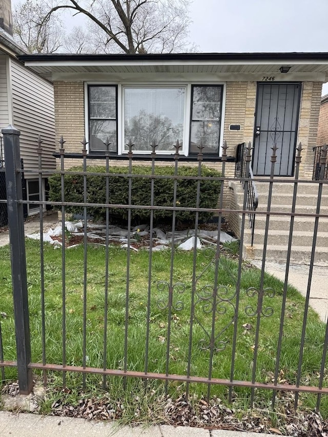 view of front of property with brick siding, a gate, fence private yard, and a front lawn