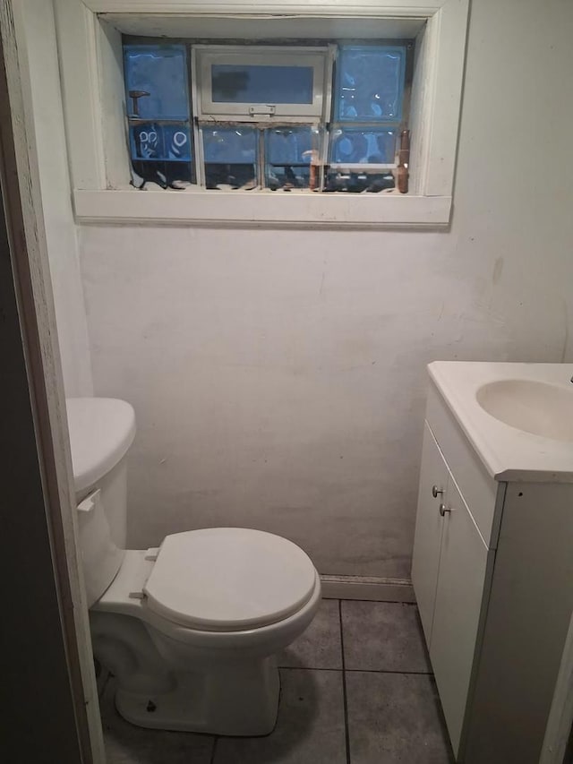 half bathroom with vanity, tile patterned floors, and toilet