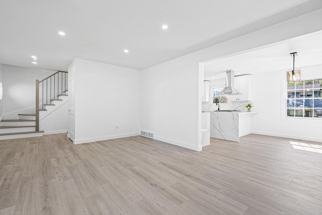 unfurnished living room with light wood-style floors, stairway, recessed lighting, and baseboards